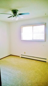 an empty room with a ceiling fan and a window